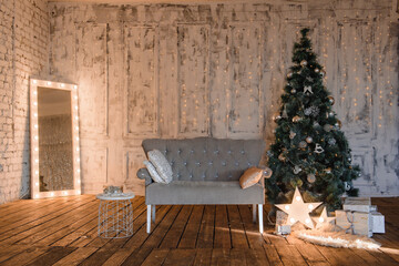 new year's interior in a classic style with a gray sofa, a Christmas tree and a mirror with light bulbs and garlands