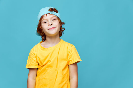 Portrait Of A Red-haired Boy Yellow T-shirt Cap On His Head Smile Cropped View