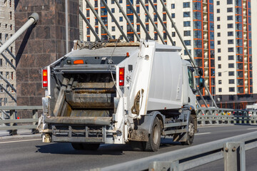 Garbage truck driving on the highway in the city, back view.