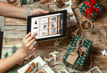 Female hands with tablet on table with hand made christmas decor