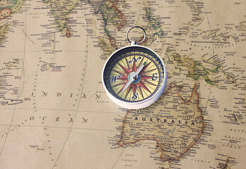 Classic round compass on background of old vintage map of world as symbol of tourism with compass, travel with compass and outdoor activities with compass