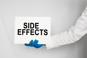 The doctor's blue - gloved hands show the word SIDE EFFECTS - . a gloved hand on a white background. Medical concept. the medicine