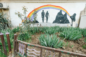 Giorgia, Tbilisi, 03.26.2018: drawing of a man and a woman under a rainbow on the hay in the garden