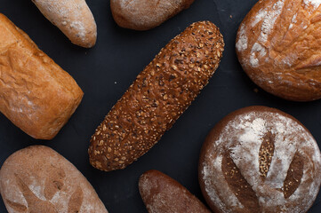 Different Freshly baked breads on dark table.