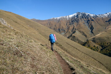 Obraz premium Tourist with a backpack walking on a mountain trail, Arkhyz, Russia.
