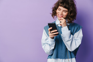 Fototapeta premium Joyful beautiful girl using smartphone and smiling