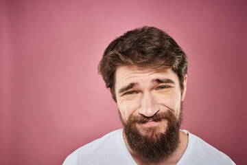 bearded man in white t-shirt emotions displeased facial expression studio pink background