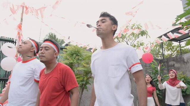 three young men seriously joined in marble and spoon race in the celebration of August 17 Indonesian Independence Day