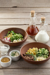 Ingredients for the traditional Russian cold soup okroshka Cucumbers, eggs, dill, onions, sour cream on wooden table