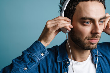 Unshaven handsome guy listening music with headphones