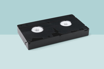 The VHS tape lies on a two-color light turquoise background.