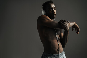 African american sportsman using headphones while stretching his arm