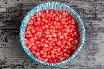 Pomegranate fruit with a blue bowl and black background
