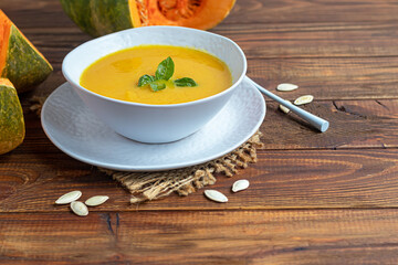 Fresh pumpkin cream soup with sour cream. Autumn lunch concept. On a wooden background. A dietary, healthy dish.