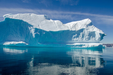 Iceberg floating in a blue and calm sea in a sunny day