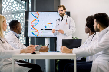 Team of multiethnic doctors having a meeting, looking at their colleague, young Caucasian man doctor or biochemist, showing on the screen some biochemical formulas. Medicine, science concept