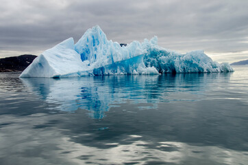 Bluish iceberg in a calm sea and a cloudy day