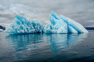 Bluish iceberg in a calm sea with the sky covered