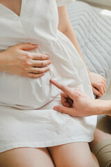 Obraz na płótnie Canvas a man's hand gently touches a woman's pregnant belly
