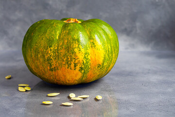 Fresh pumpkin on a gray background with pumpkin seeds. Autumn lunch concept. On a wooden background. Healthy dietary product.