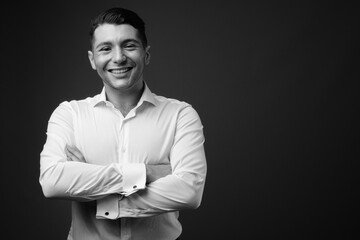 Portrait of young handsome businessman against gray background