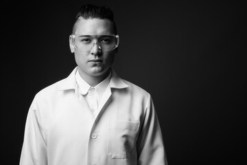 Young handsome multi ethnic man doctor against gray background