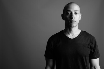 Handsome bald man wearing black shirt against gray background