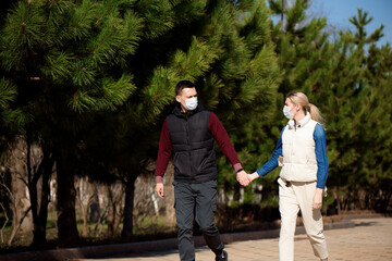 Fototapeta premium Young European man and woman in protective disposable medical mask walking outdoors afraid of dangerous NCoV 2019 influenza coronavirus mutated and spreading in China