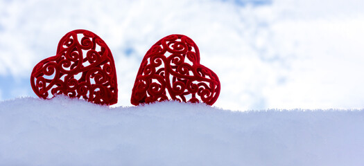 banner with two red plush hearts in a snowdrift on the background of a cloudy sky with a copy space