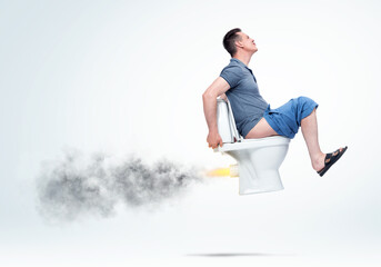 Funny man in a T-shirt and shorts sitting on the toilet and pushing flies upward, spewing out flame and smoke. On light background.