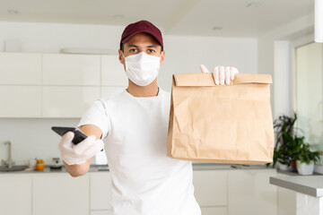 Fototapeta na wymiar Courier, delivery man in medical latex gloves and mask safely delivers online purchases in white box to the door during the coronavirus epidemic, COVID-19. Stay home, safe concept.