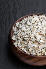 Organic barley flakes in wooden bowl isolated on white