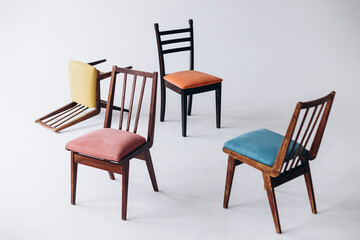 many different chairs of different colors stand at the white wall, selective focus, copy space