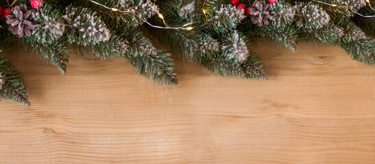 New year's banner with fir branches and lights on a wooden background. Space for text