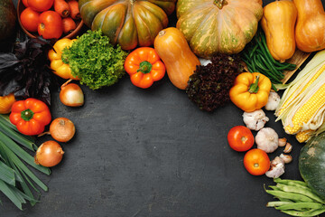 Autumn vegetable composition with pumpkin, corn and pepper on black background