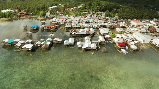 Fishing village with wooden houses standing on stilts in the sea from above. Dapa, Siargao, Philippines.