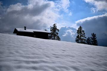Winterlandschaft mit einsamer Berghütte mit Blick auf den Latemar in den Dolomiten