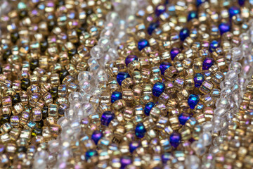 Woven bracelet made of aged multi-colored beads. Beautiful handmade shiny background. Traditional hobby.