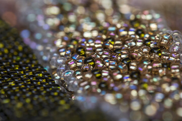 Woven bracelet made of aged multi-colored beads. Beautiful handmade shiny background. Traditional hobby.