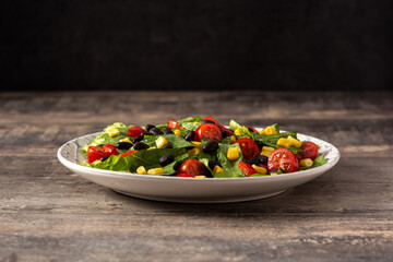 Mexican salad with black beans, corn,tomatoes,lettuce and pepper on wooden table	