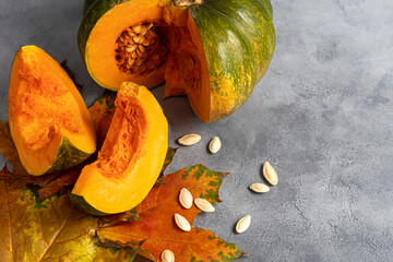 Fresh pumpkin on a gray background with pumpkin seeds. Autumn lunch concept. On a wooden...