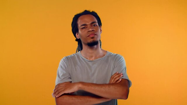 Serious young African American man 20s wearing basic casual empty blank gray t-shirt standing showing stop gesture with crossed hands, asks not to bother him on orange background studio.