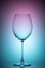The wine glass is empty with purple and blue color filters. Photo of glass on the lumen with filters. Vertical photo