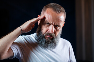 Emotional portrait of an adult gray-haired man with a beard in a white t-shirt