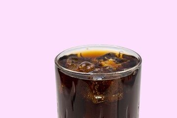 Close up view of top of full glass of soda with ice cubes isolated on pink background. Unhealthy drinks concept. Health concept. Beverage concept.