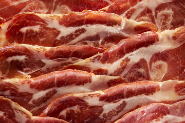 Sliced basturma cold cuts with fat lying regularly piece to piece. Gourmet meat closeup. Top view