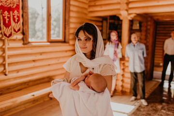  rite of sacrament of epiphany child baby in church. A mother is holding a newborn child in her...