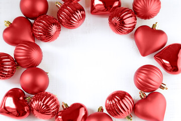 Top view of different shape red christmas ornaments on a white wooden table with copy space
