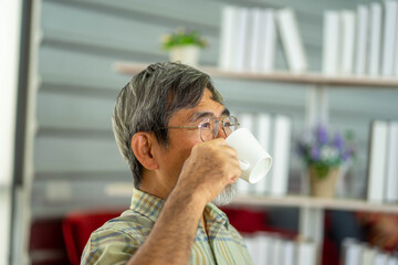 senior Asian man drinking hot coffee from white ceramic cup in  meeting at home for christmas and new year traditional festival party.