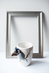 white ceramic mug with a picture of a mouse stands on a table with a gray on a white background